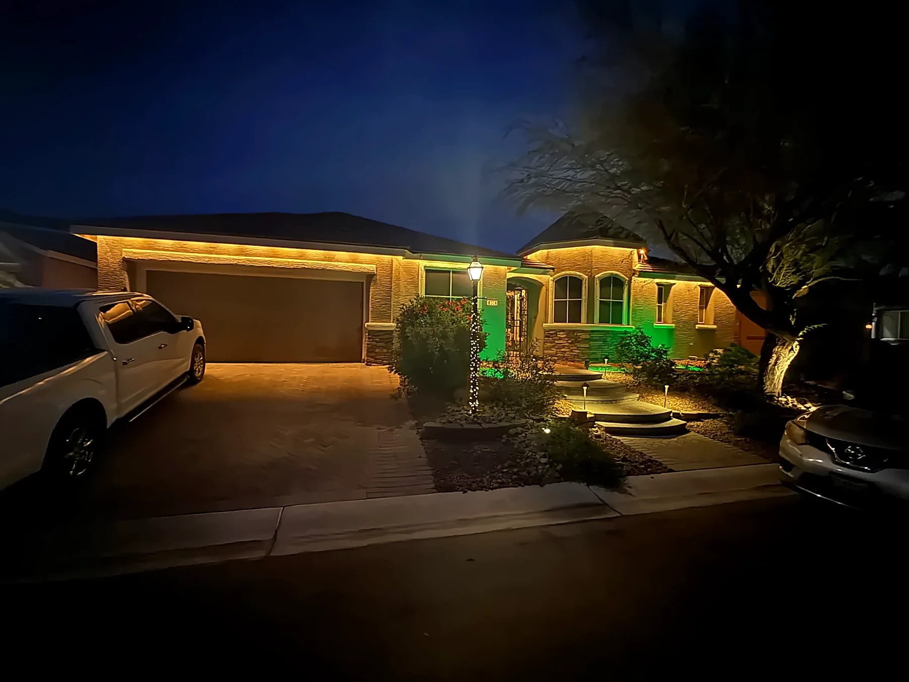 Single-story home with warm white roofline lights and green accent lighting
